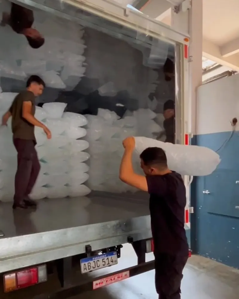 Dos personas cargan bolsas de hielo de 20 kg en el camión refrigerado de AspiBlock