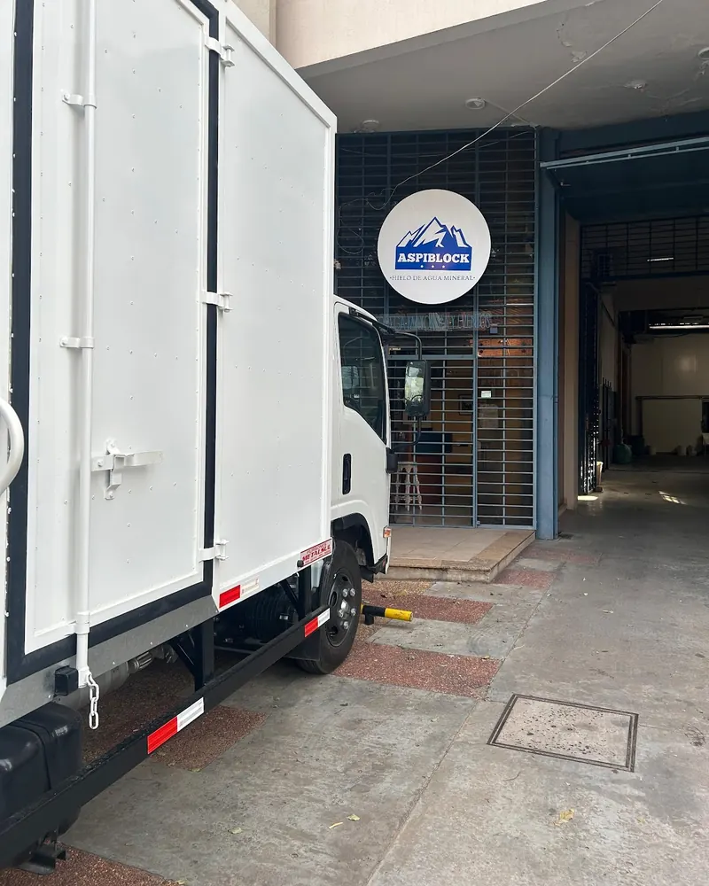 Entrada de la fábrica de AspiBlock en Asunción, con el cartel redondo de la marca y un camión